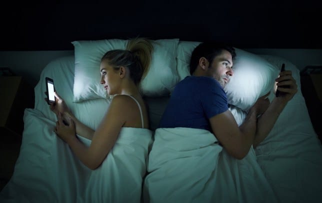 Pariskunta on vuoteessa selät toisiinsa päin, kumpikin katselee kännykkäänsä, joista tulee makuuhuoneeseen paljon valoa. Tarkoitus lienee käydä nukkumaan.